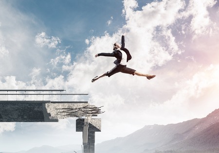 Business woman jumping over huge gap in concrete bridge as symbol of overcoming challenges. Skyscape and nature view on background. 3D rendering.の写真素材