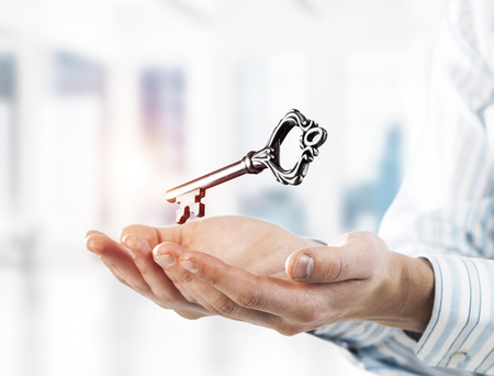 Close up of businessman hands holding old key as symbo for success. Mixed mediaの写真素材