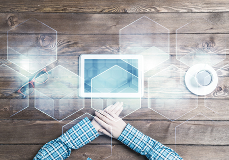 Top view of woman in checked shirt sitting at table and tablet deviceの写真素材