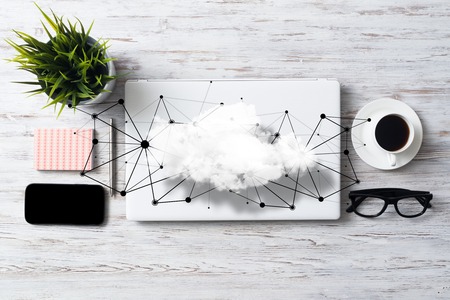 Top view of modern workplace with office stuff, social network connections and clouds above as symbol of still office life. Mixed media.の写真素材