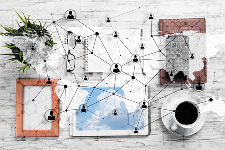 Top view of modern workplace with office stuff and global map with social connections above. Mixed media.の写真素材