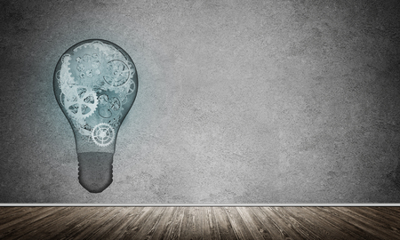 Glass lightbulb with multiple gears inside placed in empty room with grey wall on background. 3D rendering.の写真素材