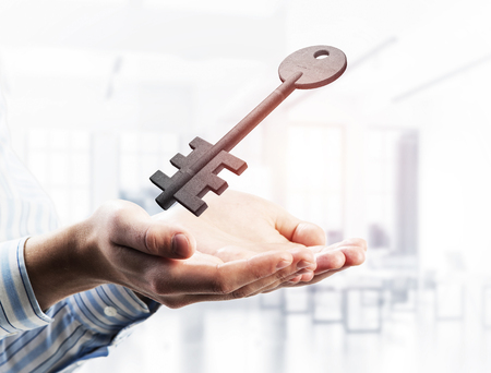 Cropped image of businessman in suit keeping stone key symbol in hands. Mixed mediaの写真素材