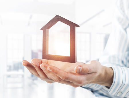 Cropped image of businessman in suit keeping stone house symbol in hands. Mixed mediaの写真素材