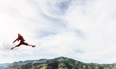Attractive business woman in suit jumping in the air as symbol of active life position. Skyscape and nature view on background. 3D rendering.の写真素材