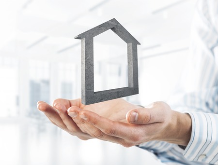 Cropped image of businessman in suit keeping stone house symbol in hands. Mixed mediaの写真素材
