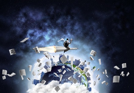 Conceptual image of young businessman in suit flying on rocket among flying papers with planet Earth and open space on background.の写真素材