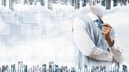 Double exposure of confident and young businessman in smart-casual wear smoking pipe and modern cityscape with business and media interface. Concept of new technologies for modern business.の写真素材