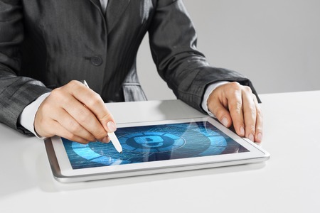 Close up of businesswoman sitting at atble and working on tablet pcの写真素材