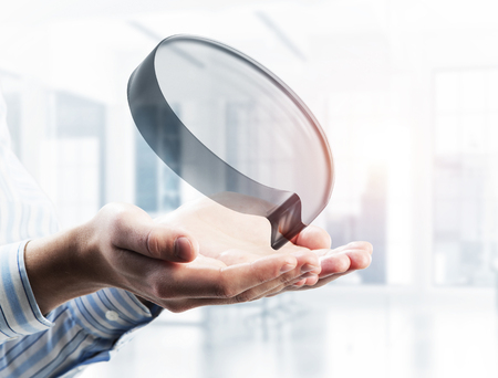 Close of businessman hands showing glass speech bubble as internet concept. Mixed mediaの写真素材