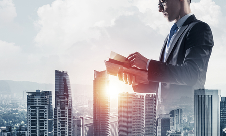 Double exposure of elegant businessman with diary in hands looking awayの写真素材