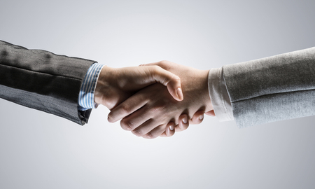 Close of business people shaking hands as symbol for partnership. Mixed mediaの写真素材