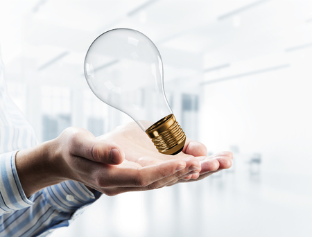 Close up of businessman holding in hands glass light bulb. Mixed mediaの写真素材