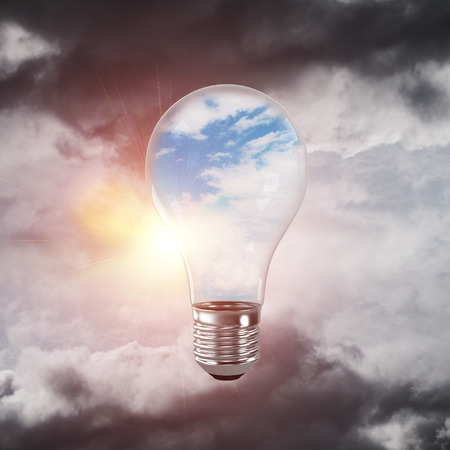 Glass lightbulb with clouds inside with grey cloudly skyscape on background. 3D rendering.の写真素材
