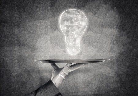 Closeup of waitress's hand in glove presenting sketched business plan in form of lightbulb on metal...