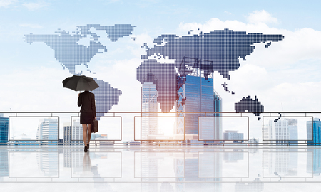 Back view of businesswoman with black umbrella looking at city. Mixed mediaの写真素材