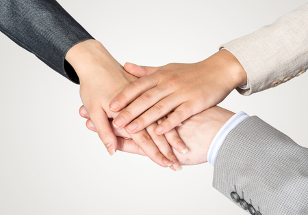 Close up of businesspeople putting their hands together against white background
