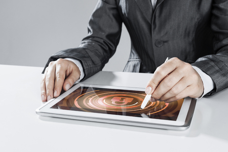Close up of businesswoman sitting at atble and working on tablet pcの写真素材