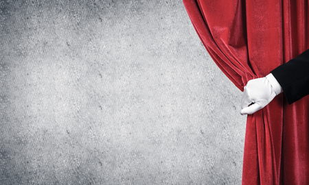 Close up of hand in white glove open red velvet curtainの写真素材
