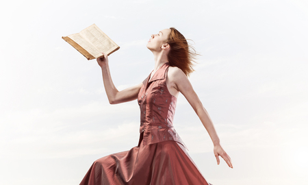 Young woman in red long dress with book in handの写真素材
