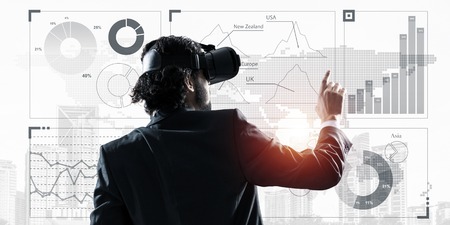 Young businessman in virtual helmet using media panel. Mixed mediaの写真素材