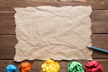 Crumpled brown paper sheet and pencil on wooden tableの写真素材