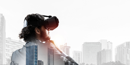 Double exposure of businessman in virtual helmet against cityscape backgroundの写真素材