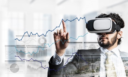 Young handsome businessman in virtual helmet against cityscape backgroundの写真素材