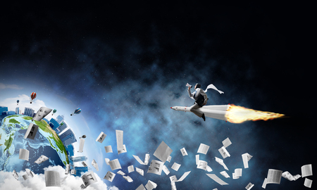 Conceptual image of young businessman in suit flying on rocket among flying papers with planet Earth and open space on background. Elements of this image are furnished by NASA.の写真素材