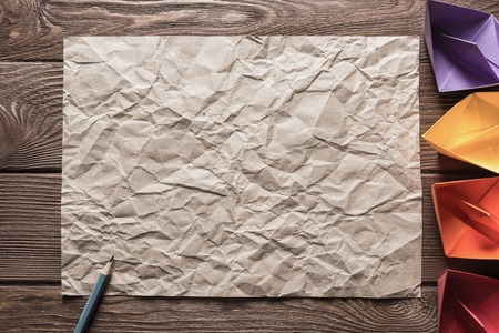 Crumpled brown paper sheet and pencil on wooden tableの写真素材
