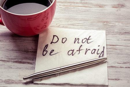 Cup of coffee and napkin with message on wooden tableの写真素材