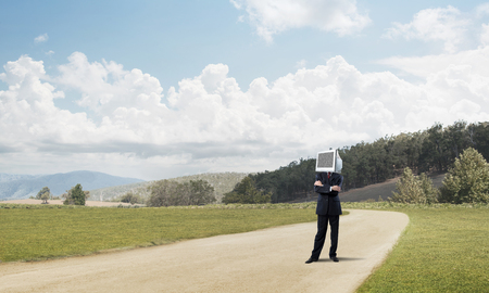 Businessman in suit with monitor on the head keeping arms crossed while standing on the road.の写真素材