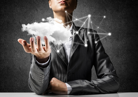 Businessman in suit keeping cloud with network connections in hand with gray wall on background. 3D rendering.の写真素材