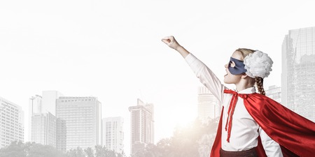Little confident child in mask and cape plays cool superheroの写真素材