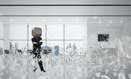 Businessman in suit with an old TV instead of head keeping arms crossed while standing among flying letters inside office building. 3D rendering.の写真素材
