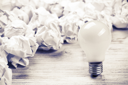 Many balls of crumpled paper and light bulb among themの写真素材