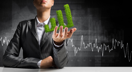 Businessman in suit presenting green plant in form of growing graph in hands with business sketches on background.の写真素材