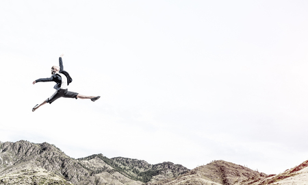 Attractive business woman in suit jumping in the air as symbol of active life position. Skyscape and nature view on background. 3D rendering.の写真素材