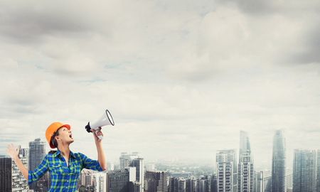 Engineer woman with megaphone on modern city landscapeの写真素材