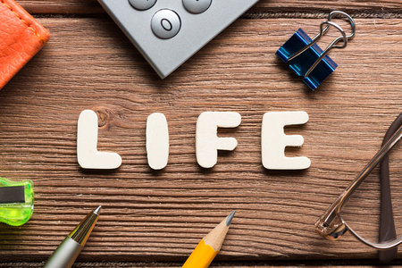Top view of business workplace with words of LIFE and office items on wooden surfaceの写真素材