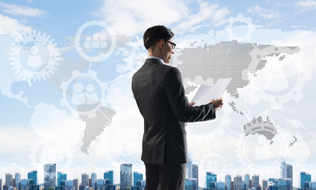 Young elegant businessman with papers in hands looking awayの写真素材