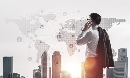 Elegant businessman standing with back and talking his mobile phoneの写真素材