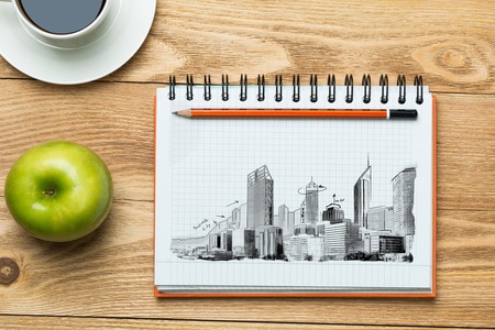 Wooden table with coffee cup and architectural sketches on notepadの写真素材