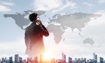 Double exposure of elegant businessman standing with back and talking his mobile phoneの写真素材
