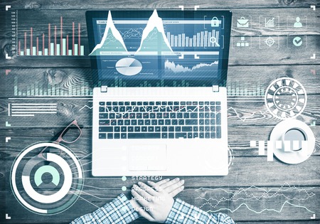 Top view of woman in checked shirt sitting at wooden table with laptopの写真素材