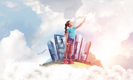 Cute kid girl on city floating island throwing paper planeの写真素材