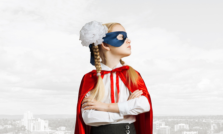 Little confident child in mask and cape plays cool superheroの写真素材