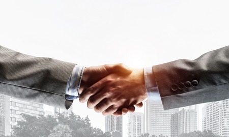 Close of business people shaking hands as symbol for partnership. Mixed mediaの写真素材