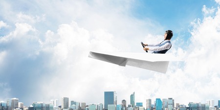 Business leadership and motivation concept with pilot sitting in paper airplane. Funny man in...