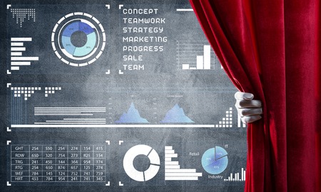 Hand opening red curtain and drawing business graphs and diagrams behind itの写真素材